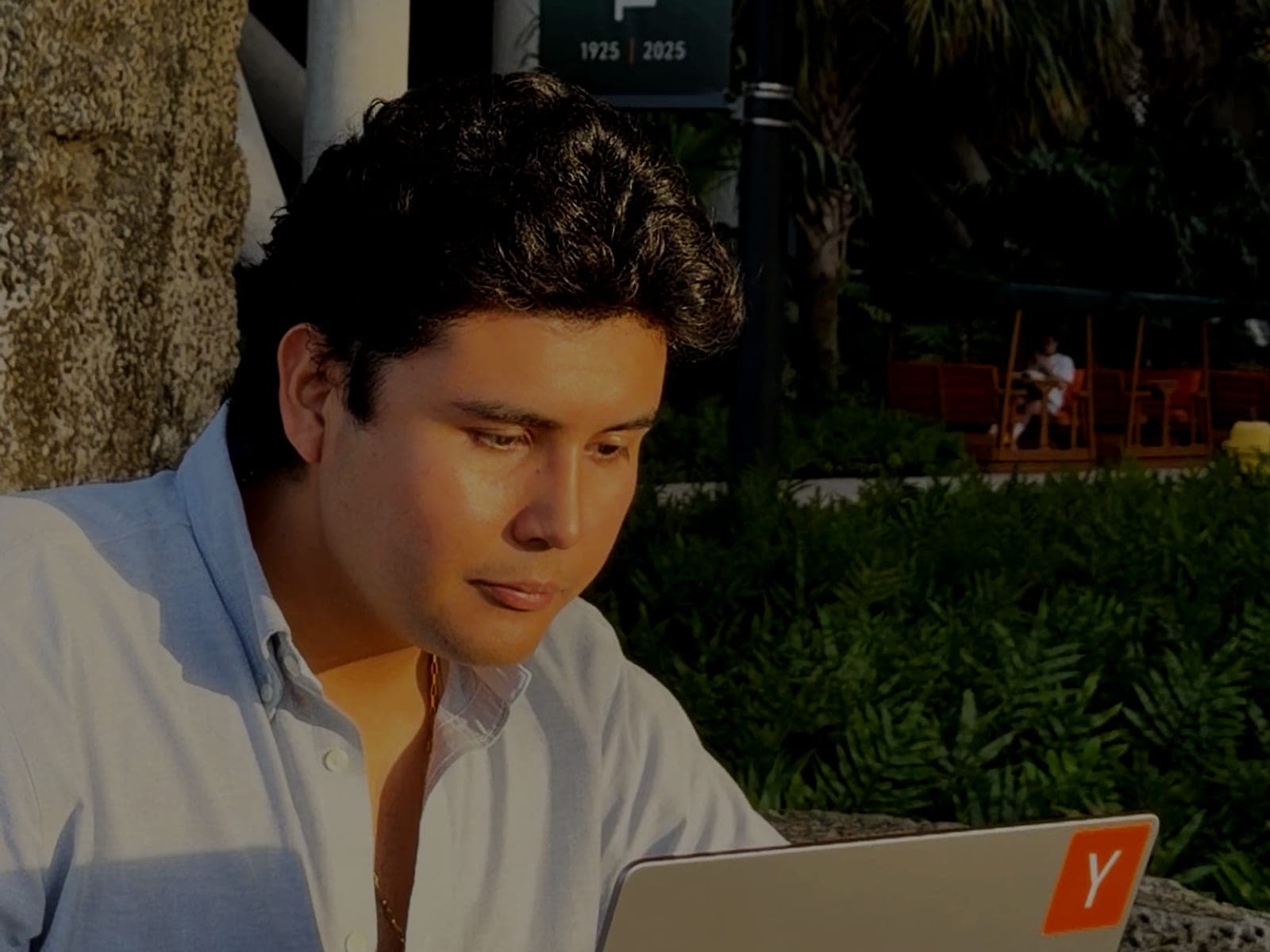 Jeffrey Escobar, founder and CTO of House AI, working on a laptop outdoors at the University of Miami