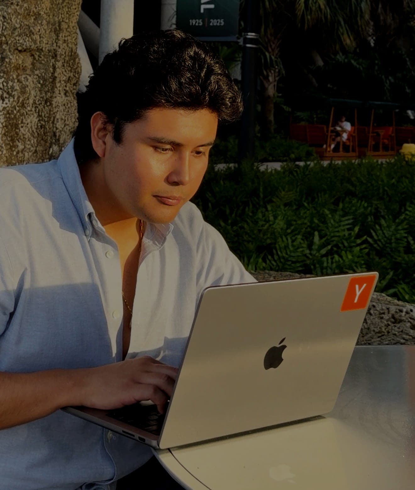 Jeffrey Escobar, founder and CTO of House AI, working on a laptop outdoors at the University of Miami
