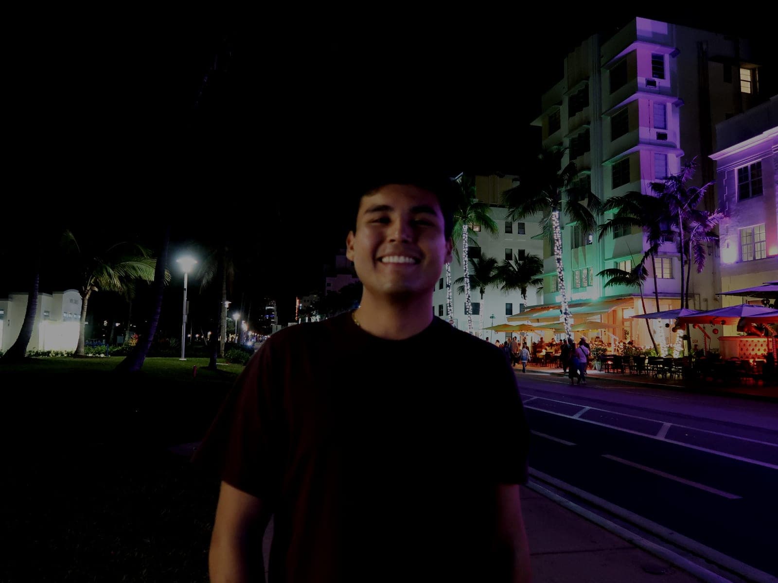 Jeffrey Escobar on Ocean Drive in Miami Beach at night, with neon-lit Art Deco hotels behind him