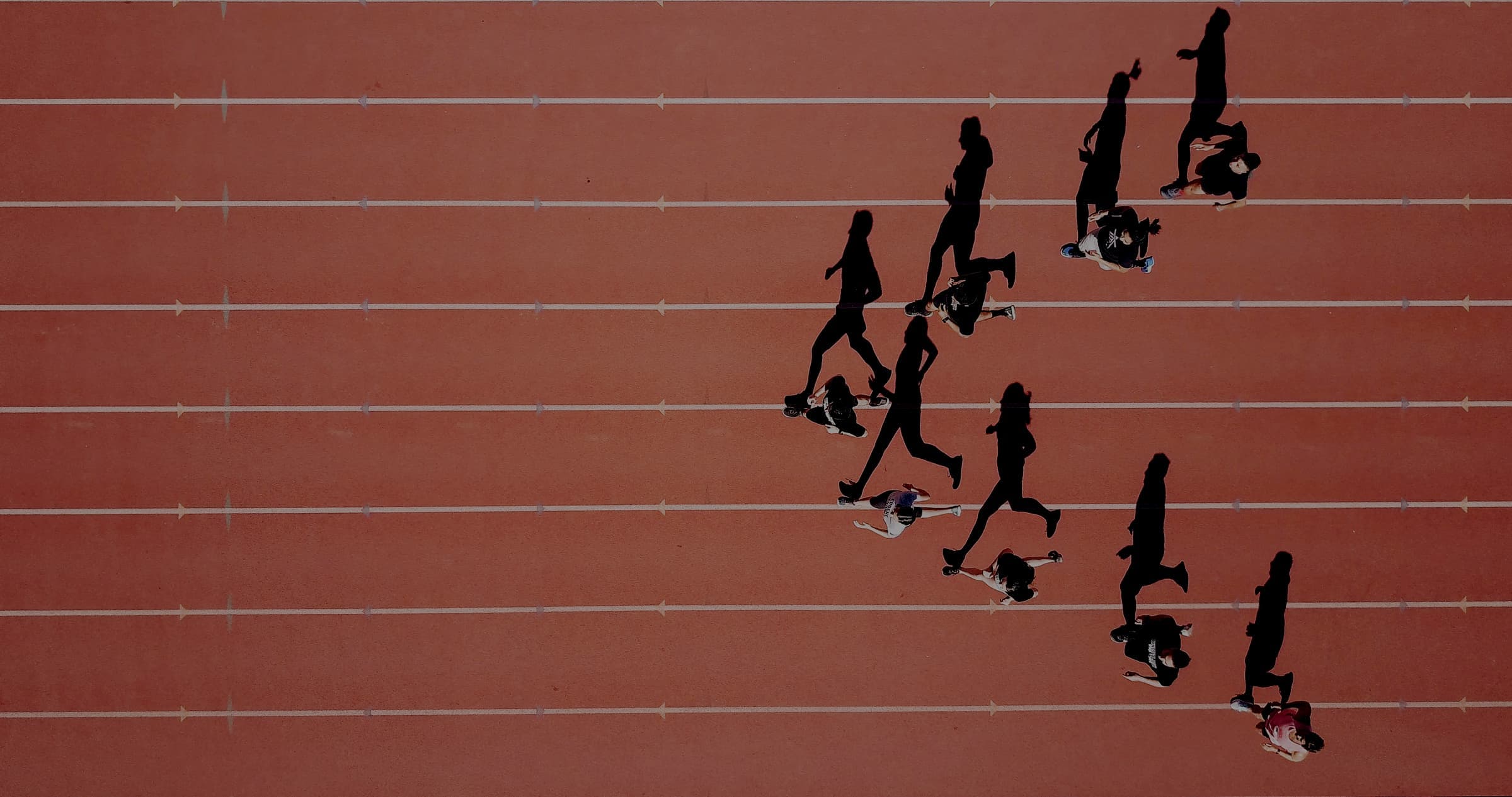 Aerial view of runners spread across a red running track